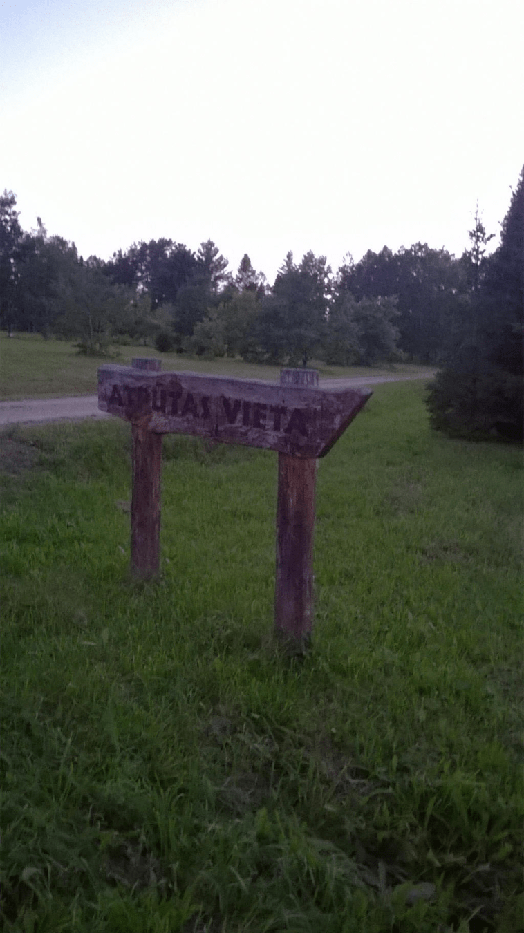 Wooden sign pointing to the rest area in the grass by the dirt road
