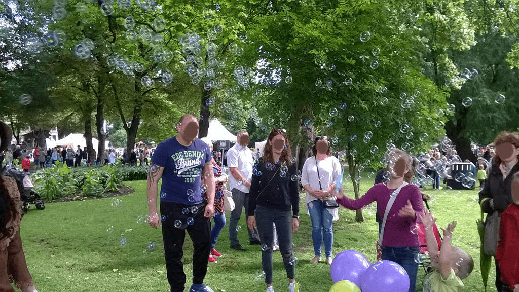 People watching bubbles being made by the fair worker
