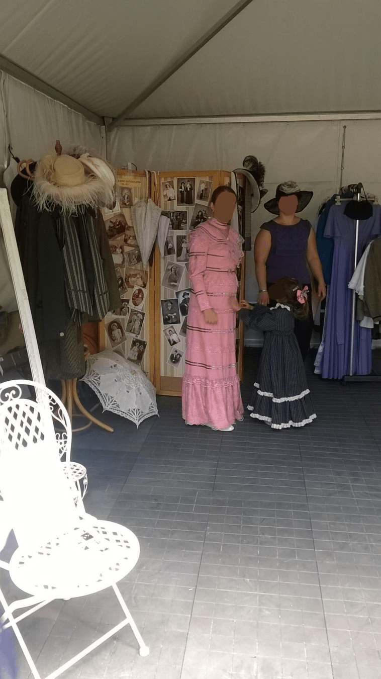 Ladies in retro outfits standing inside of the retro photo tent, surrounded by props and outfits