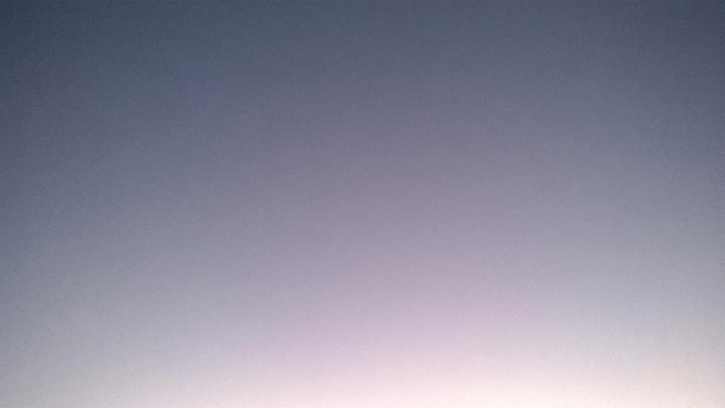 A dark-ish blue sky, tinted with the bright light of the setting sun towards the bottom