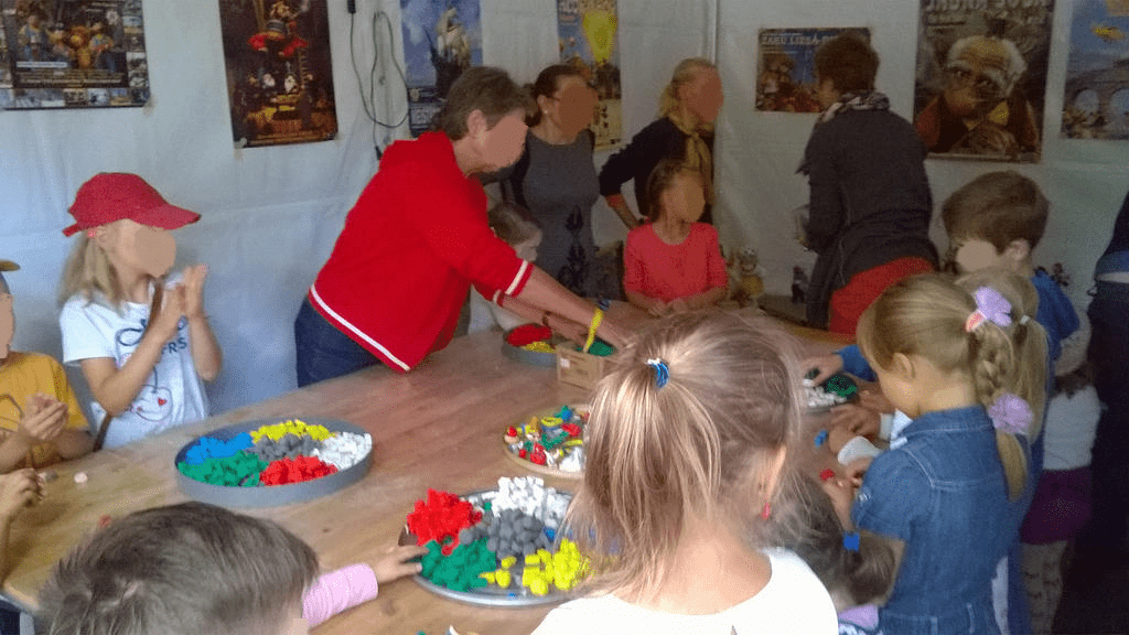 Kids and fair workers assisiting with making stuff from modeling clay