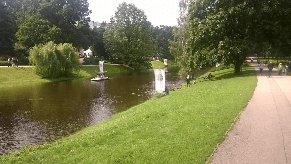 Show of the canal, with people enjoying the sunny day by lying on the grassy area