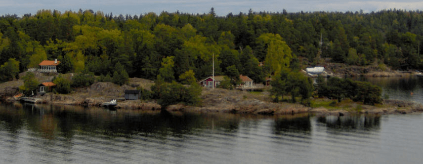 Forested and a bit stony island with homes and docks on it