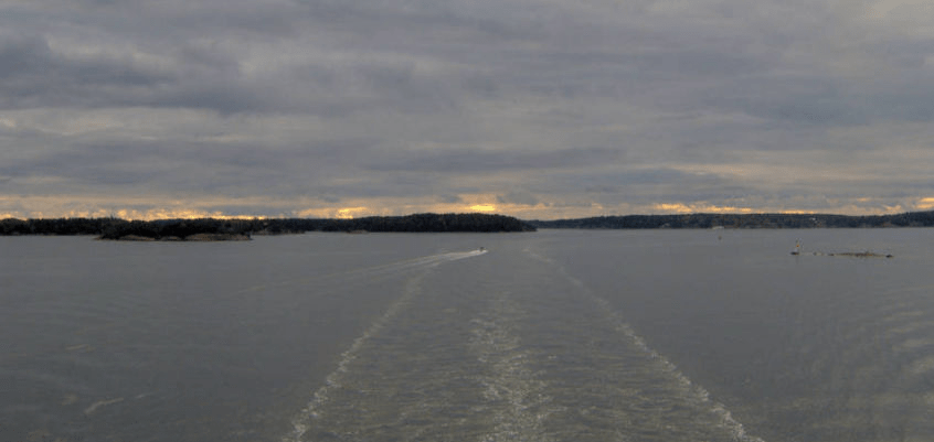 Looking out to the bay, with a ripples in the water from the cruise ship swimming through, as a boat races through