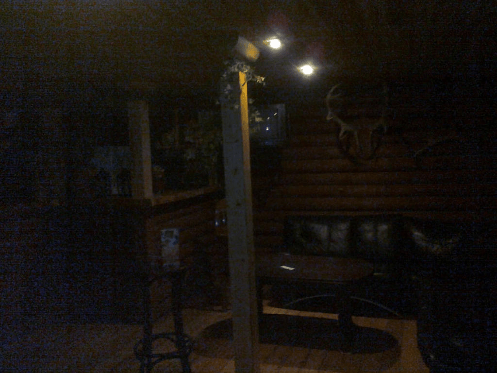 Inside of the wooden cabin, with only two lights on, the rest of the room dark