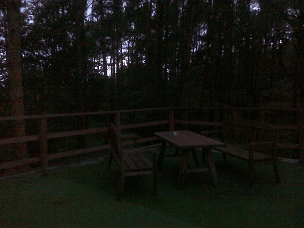 Area with a table and chairs on a balcony on the second floor of the cabin