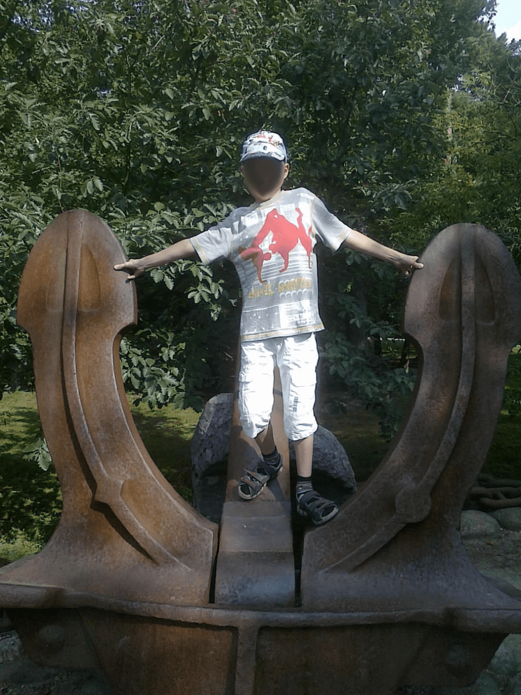 Young boy standing atop of a big anchor