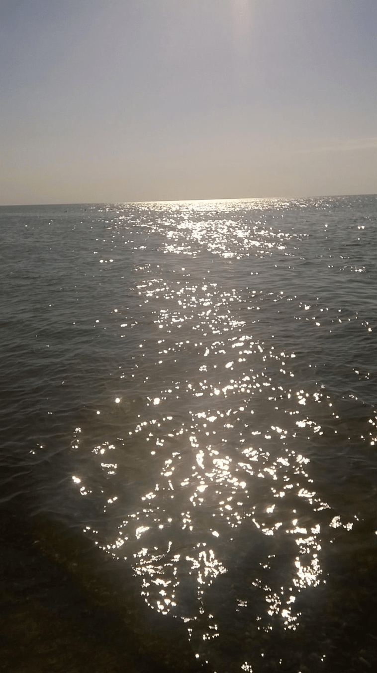 Photo of the sea with sun shining on the water like diamonds
