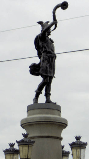 Statue of a man - possibly a viking - with a horn, on top of a bridge pillar