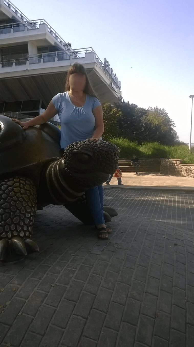 Teenager leaning on a huge metal turtle, next to a hotel, on the beach in Majori, Jurmala