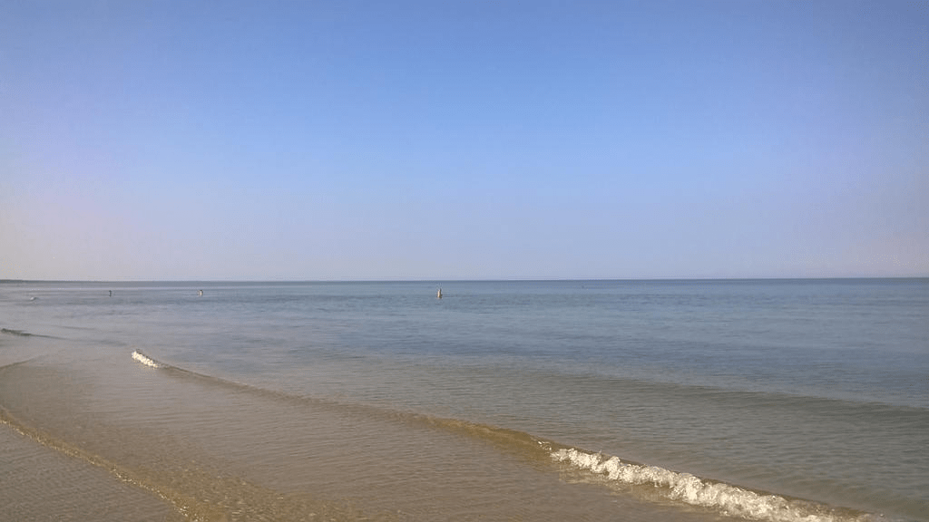 Show of the calm waters of the Gulf of Riga, with perfectly clear sky, people in the distance enjoying the water