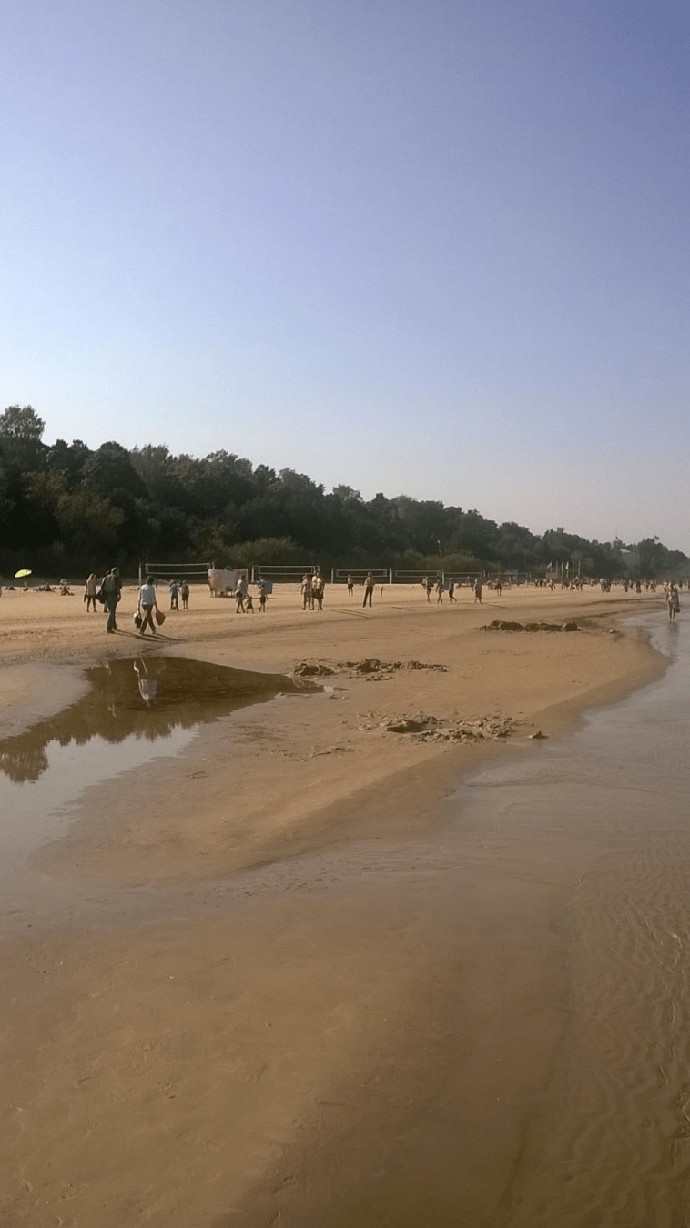 Shot of the beach in Majori, with people in varying states of dress, either sunbathing, walking or playing