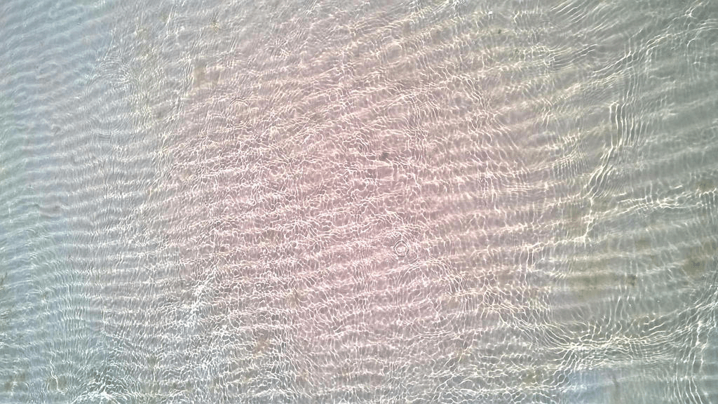 Grooved bottom of the sea in the shallows, shimmering with light with the rippling of small waves