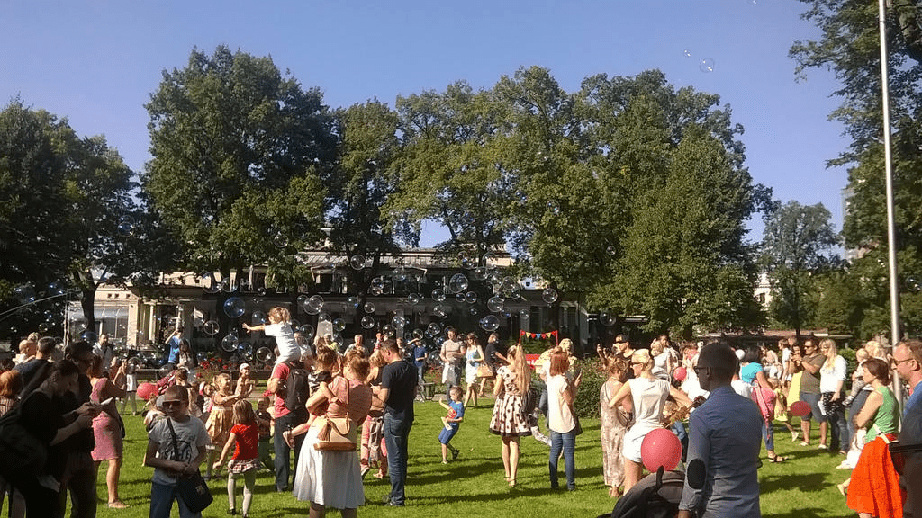 A crowd in Vermanes Garden watches as bubbles are being created and floating in the air