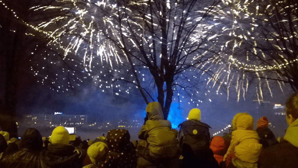 Fireworks display on the River Daugava, with a large crowd of people watching the show