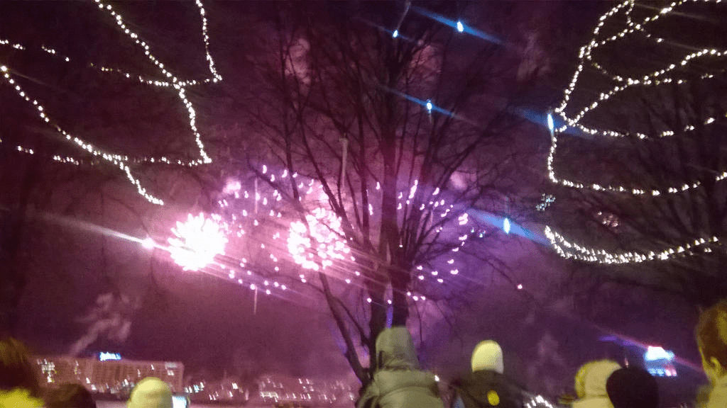 Red and purple fireworks bursting and fizzling in the sky