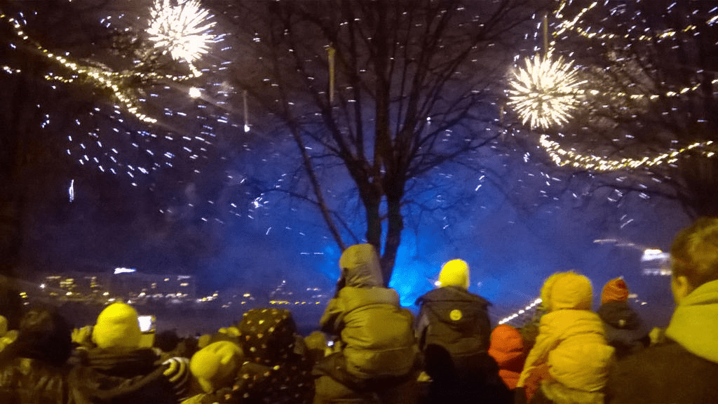 Yellow-ish fireworks with blue smoke rising from the ground