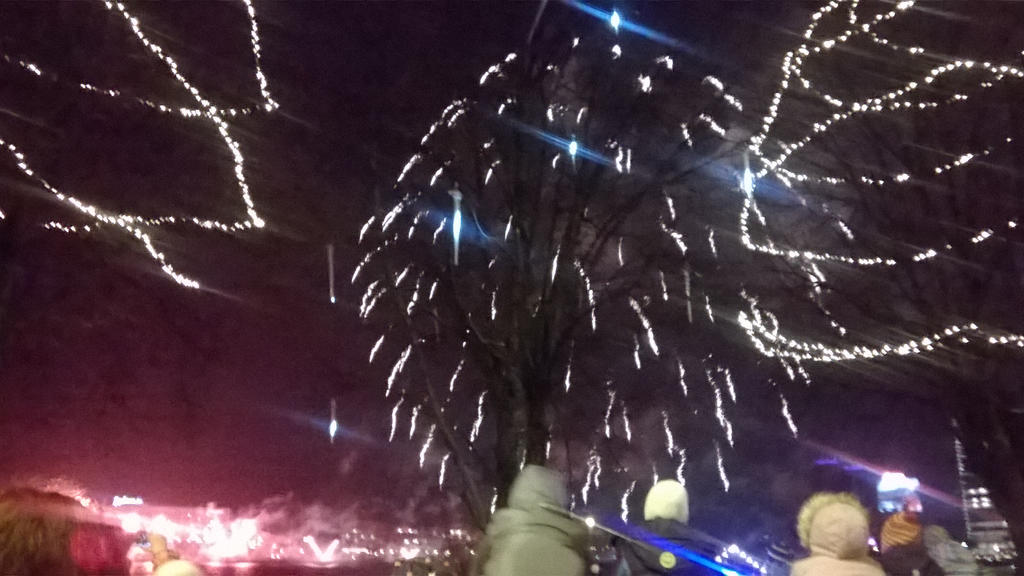 Red fireworks shooting from the ground and bright lights raining in the sky