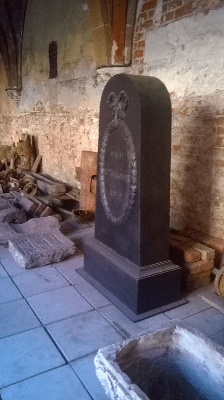 A big stone slab that looks like a tombstone, fully black with writing on the front