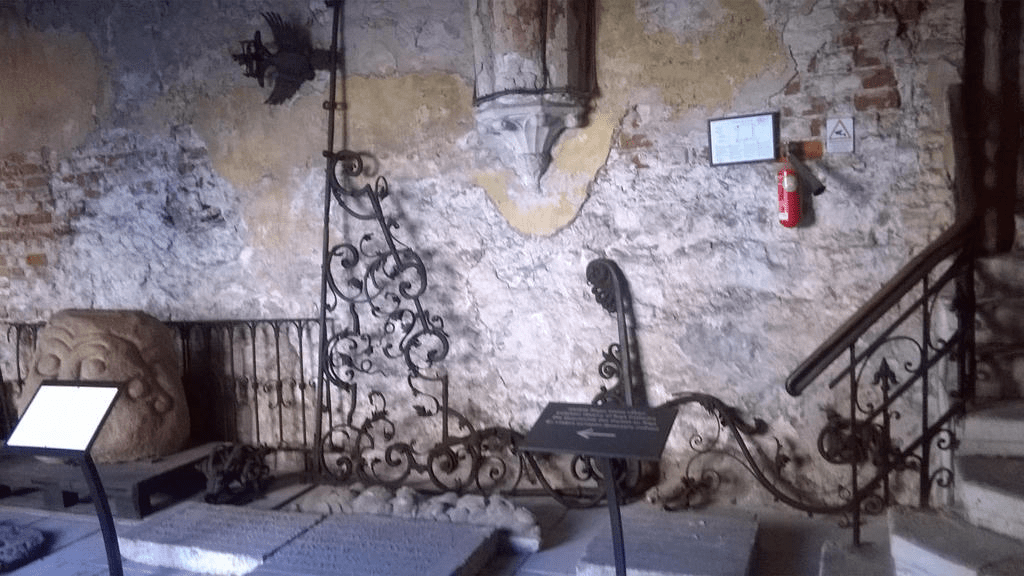 Metallic and stone decorations, like weatherwanes and heads, on the floor and by the wall