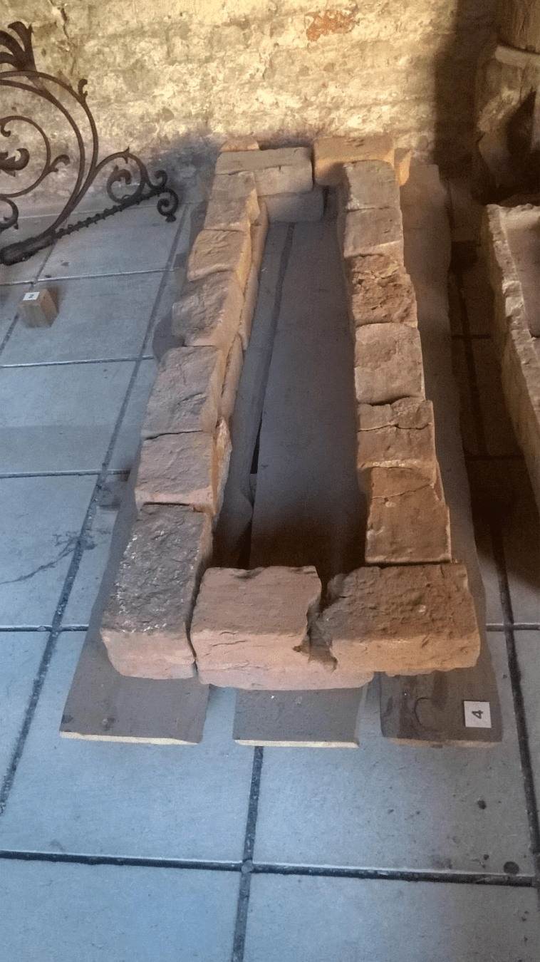 Small bricks placed in a square formation, like around a grave, placed on wooden planks and on the ground