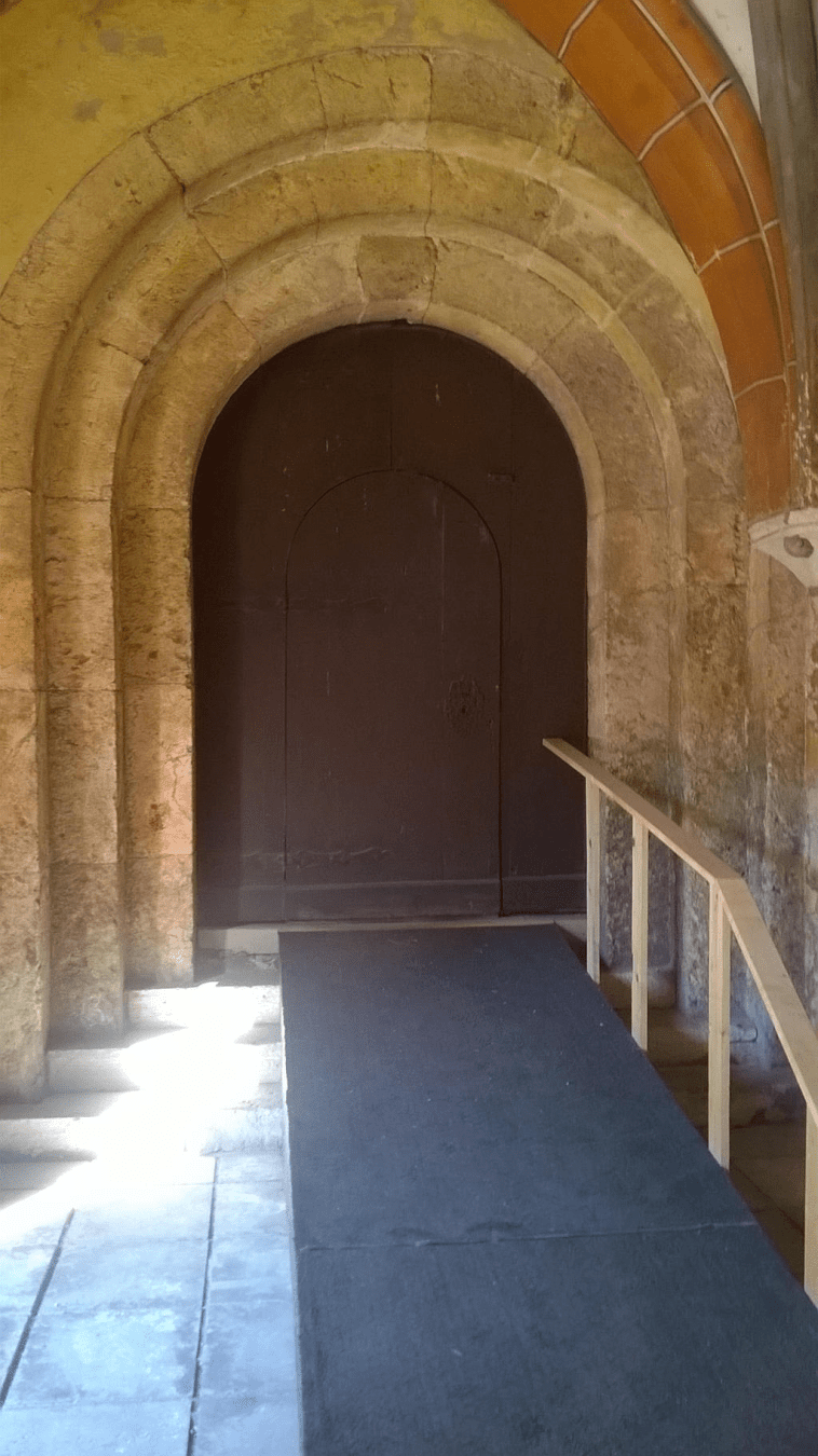 Metallic door in an old cathedral, with a ramp leading to it