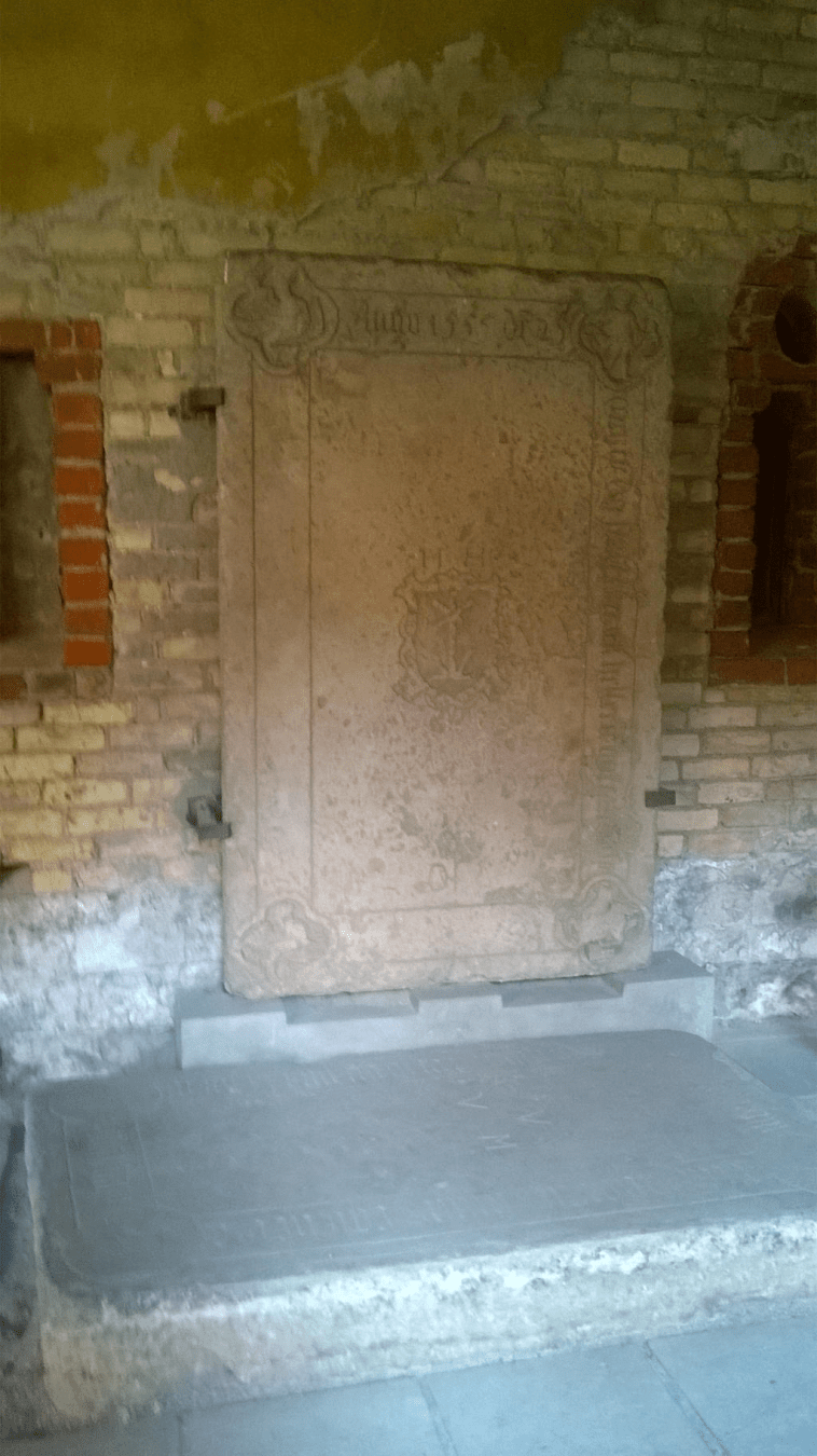 Stone slabs with latin writing, one attached to a wall and another placed on the floor