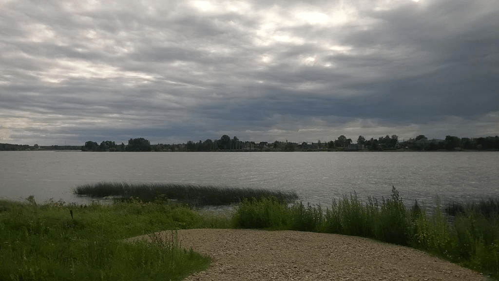 The river Daugava, with a rocky path leading to the river through the grass, the sky overcast