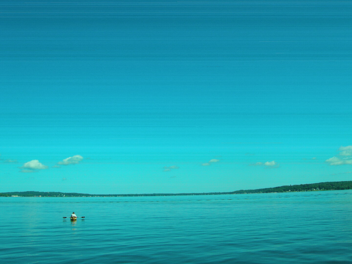 A kayaker on a lake in the morning. The image has horizontal banding.