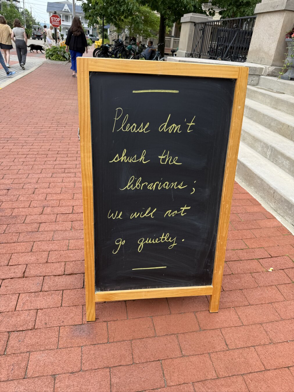 A sandwich board with chalk writing located in front of a library