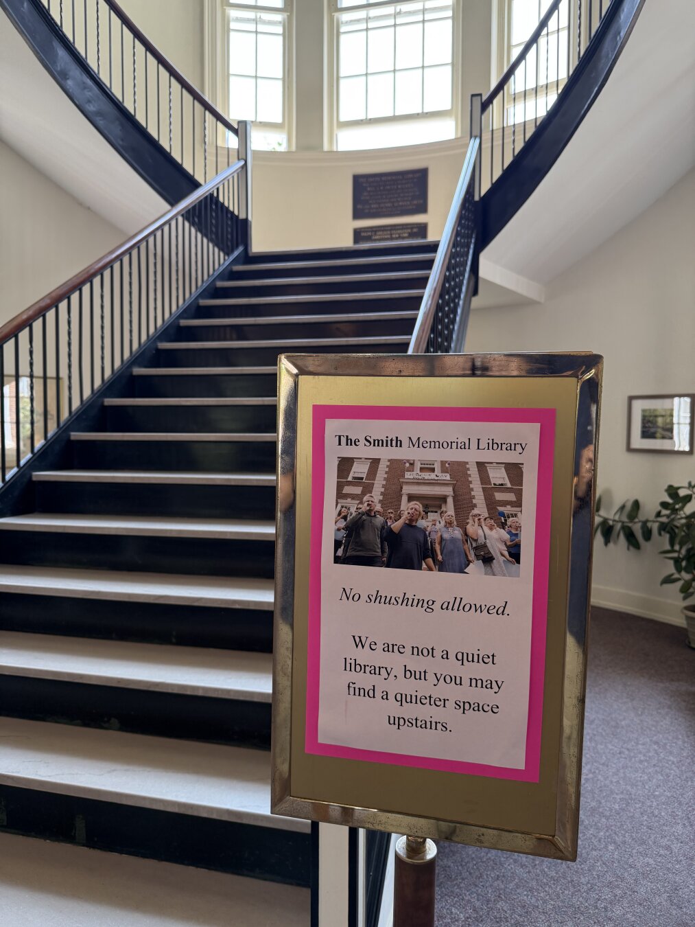 A sign in a library near a stairway