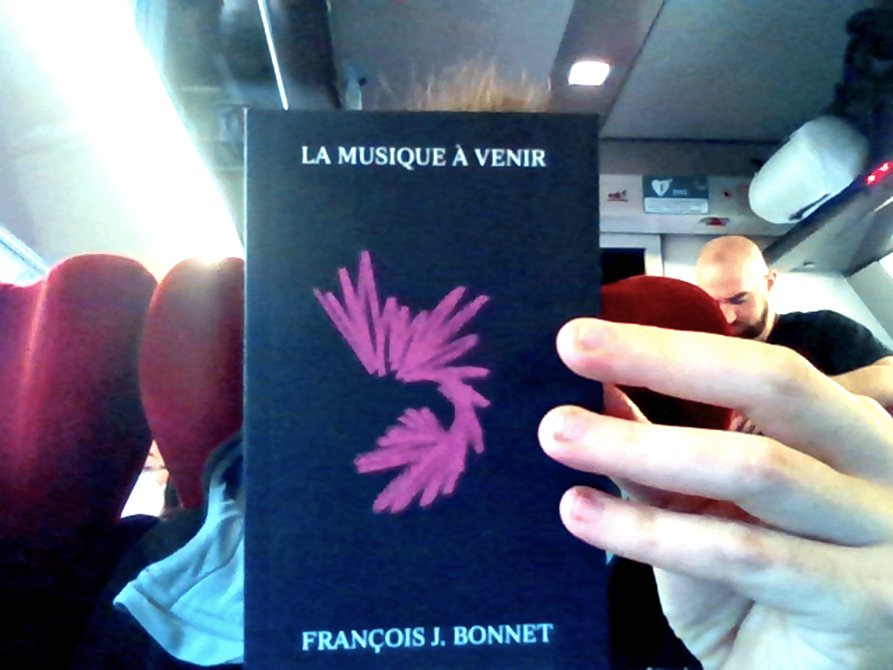 A black paper cover with a pink color pencil expressive drawing made in the train. The book is “La musique à venir by François J. Bonnet”