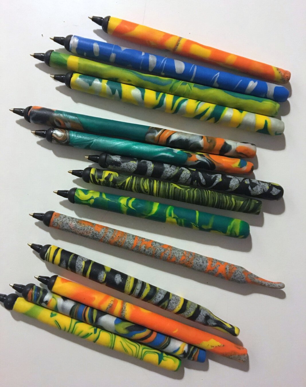 A bunch of pens made of colorful Fimo marbeling patterns.