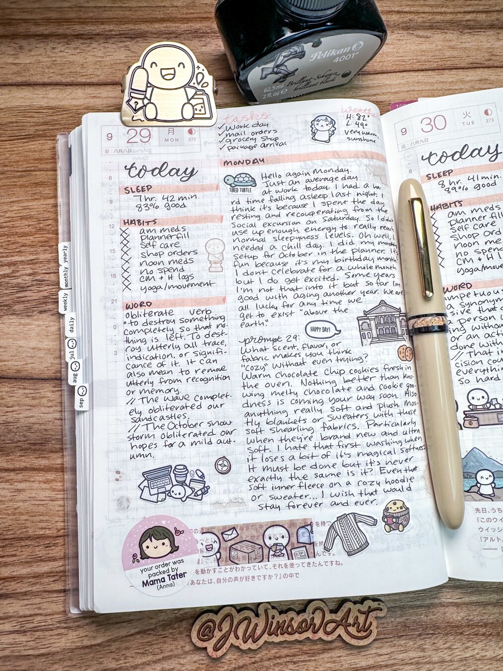 A journal page open to two days of entries, featuring handwritten notes, a sleep log, habits, and tasks. Decorative illustrations and stickers are present, including a character holding a mug. A bottle of ink and a pen are placed nearby.