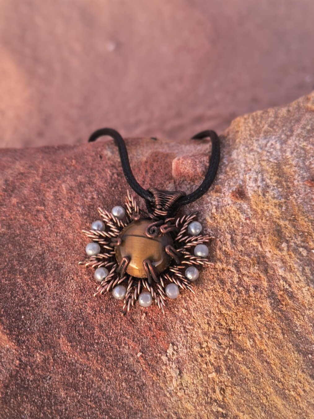 Chapter 8 — The Sun That Waits

🌅 Tiger Eye, wrapped in copper and crowned with pearls — a little sun resting on the red rocks of Broome.

People stop me to compliment it all the time. They touch the copper, tilt it to catch the light in the stone, and say “Wow.”
And yet… somehow, it’s still waiting for its person.

Maybe some pieces are patient like that — knowing exactly when and who they’re meant to follow home.

#WireWrapping #TigerEye #PearlJewelry #MalikasRealm