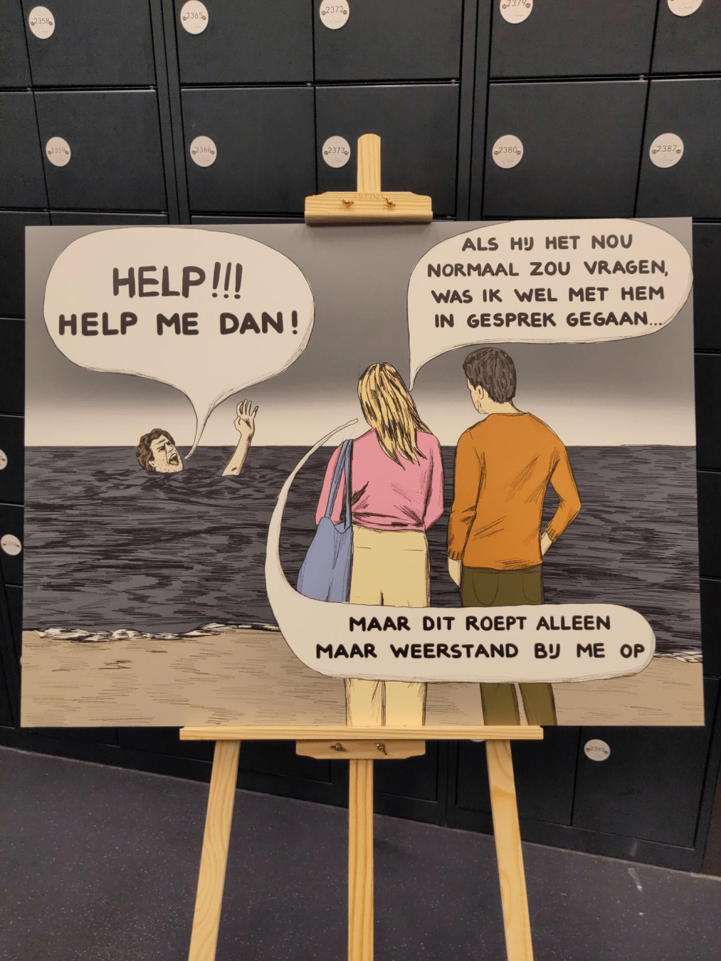 Geschilderde comic op een schildersezel. Een persoon is in het water en kan duidelijk niet zwemmen. Hen is bijna aan het verdrinken, en roept met het hoofd nog net boven het water uit: "Help! Help me dan!" Twee mensen staan aan de kant naar de verdrinkende persoon te kijken. Een van hen zegt "Als hij het nou normaal zou vragen, was ik wel met hem in gesprek gegaan. Maar dit roept alleen maar weerstand bij me op."