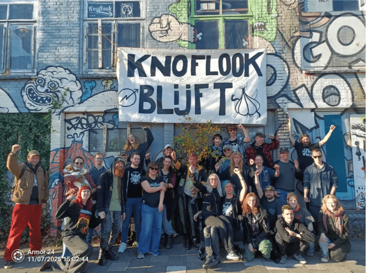 Groepsfoto van de Knoflook in Den Bosch met boven de ingang het spandoek "Knoflook blijft"