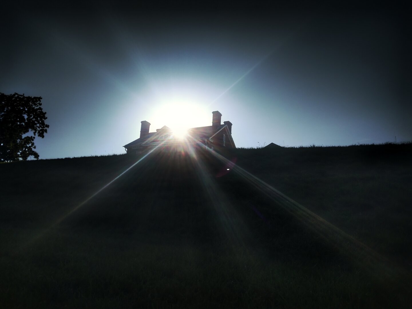 Carroll Park in Baltimore. The sun shining just behind a building (called the mansion) that sits on a hill.