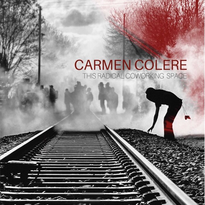 Une photo d'un individu qui ramasse un objet le long d'une voie ferrée. En arrière plan il ya un groupe de personnes au milieu d'une fumée de gaz lacrymo. C'est une photo de manif en noir et blanc.