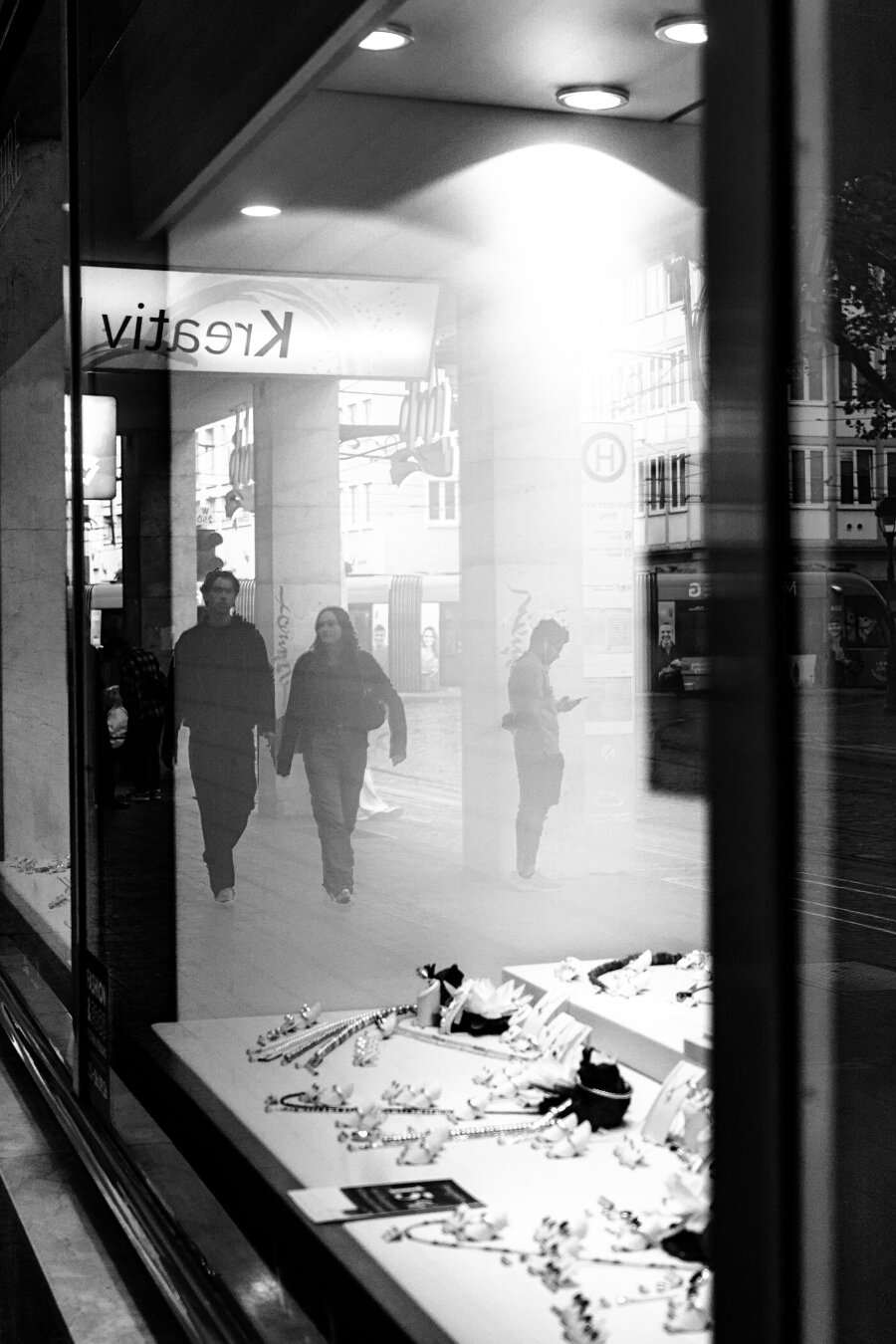A couple is reflected in the window of a jewelry store