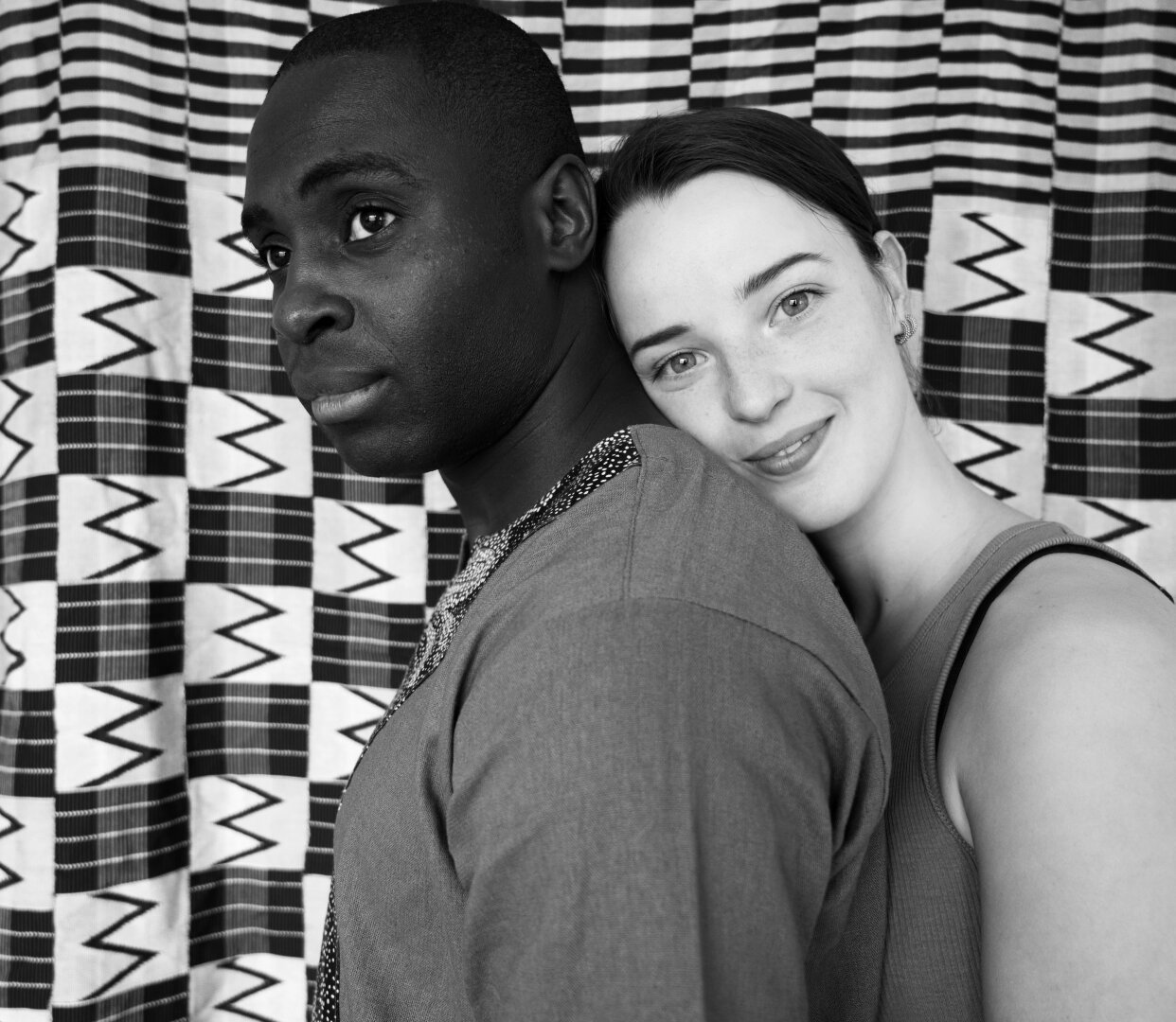 My brother and his girlfriend. She rests her face on his neck from the back and they are placed in a background of kente cloth