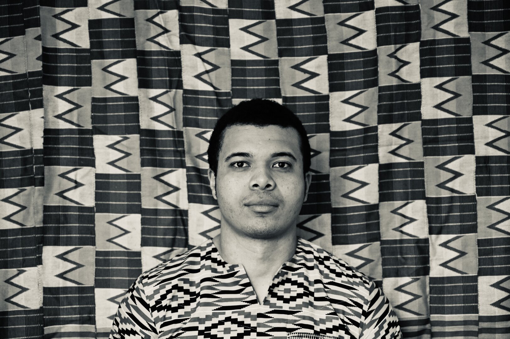 My brother Olivier facing the camera with the background of kente cloth