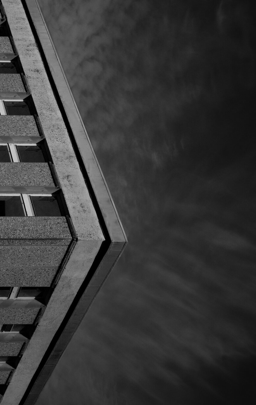 Dramatic clouds over the corner of a building, rotated and cropped for an abstract image.