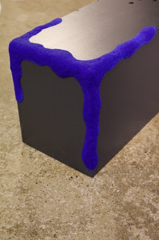 une sculpture cubique grise avec rebord bleu en papier maché