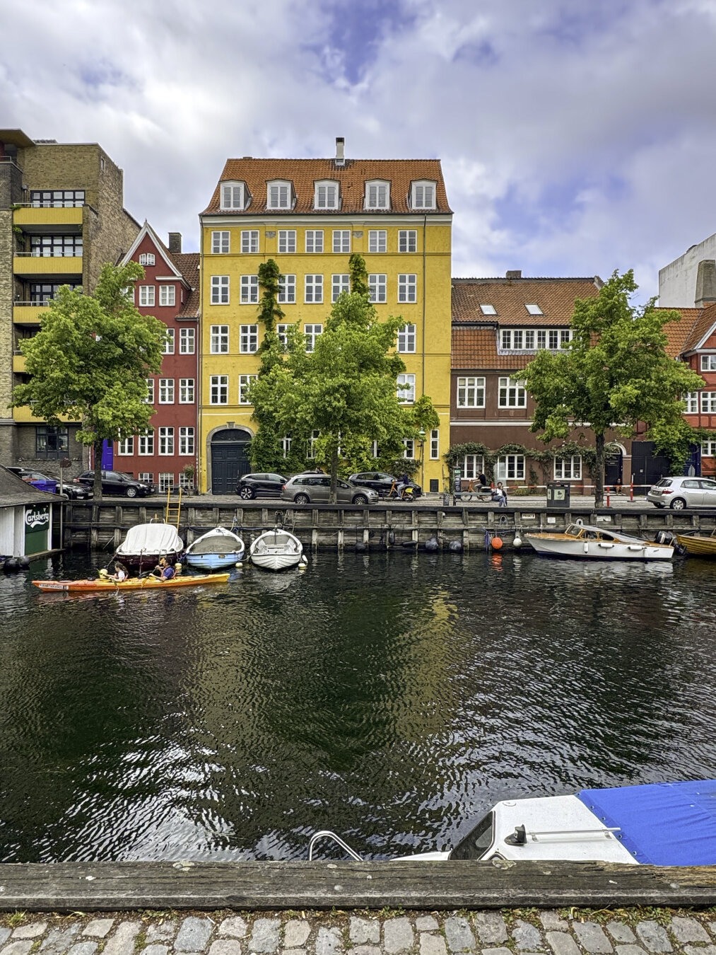 Colorful buildings in yellow and red overlook a small waterway lined with boats.