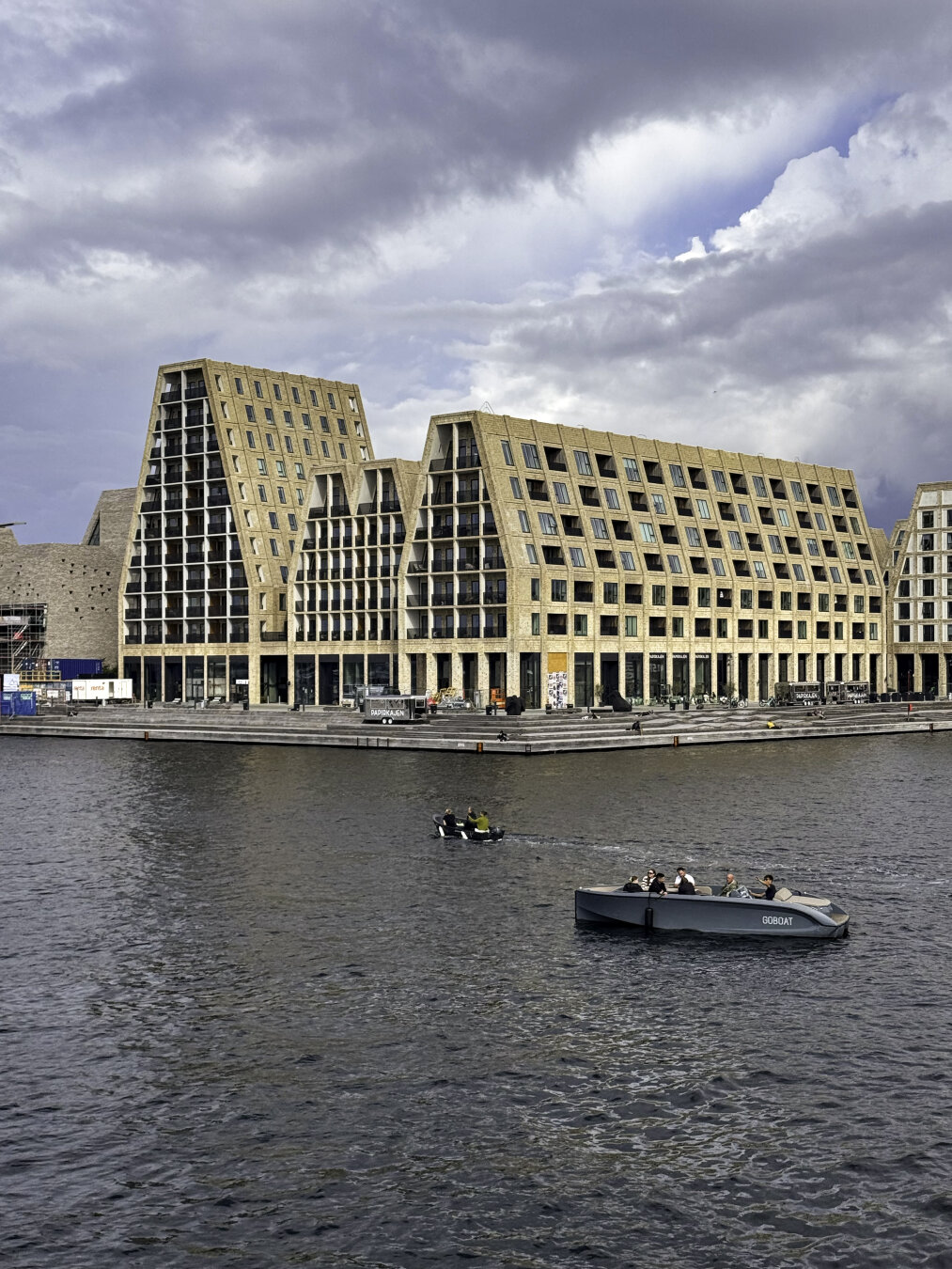 Several modern buildings with a structural design to mimic peaked roofs but with windows that extend up to the top of each peak.