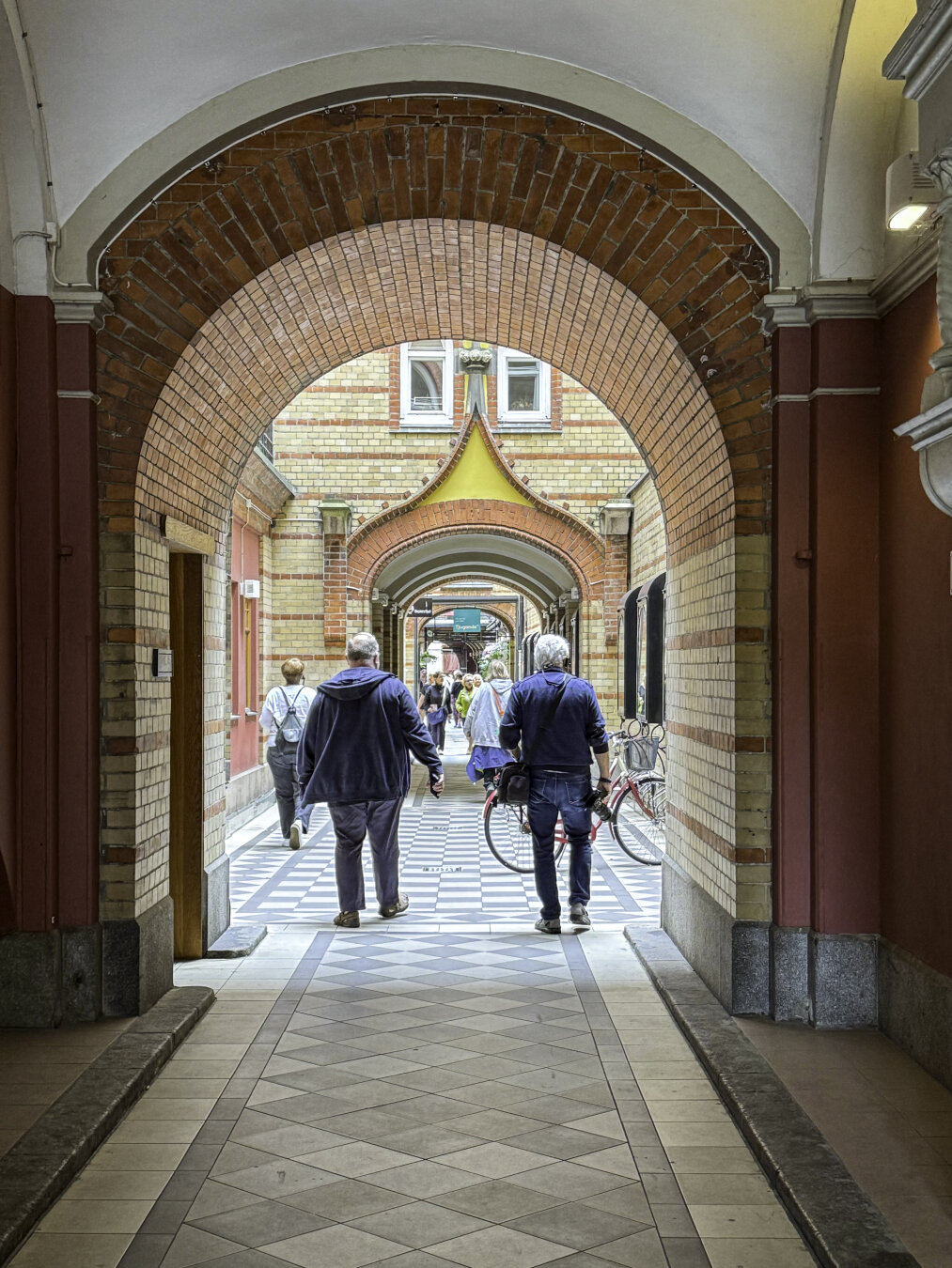 A pedestrian passage through a series of historic buildings with brick walls and a series of different types of brick arches.