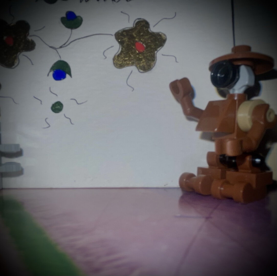 Droïde Lego marron devant un décor de fleur dorée. Levant son bras