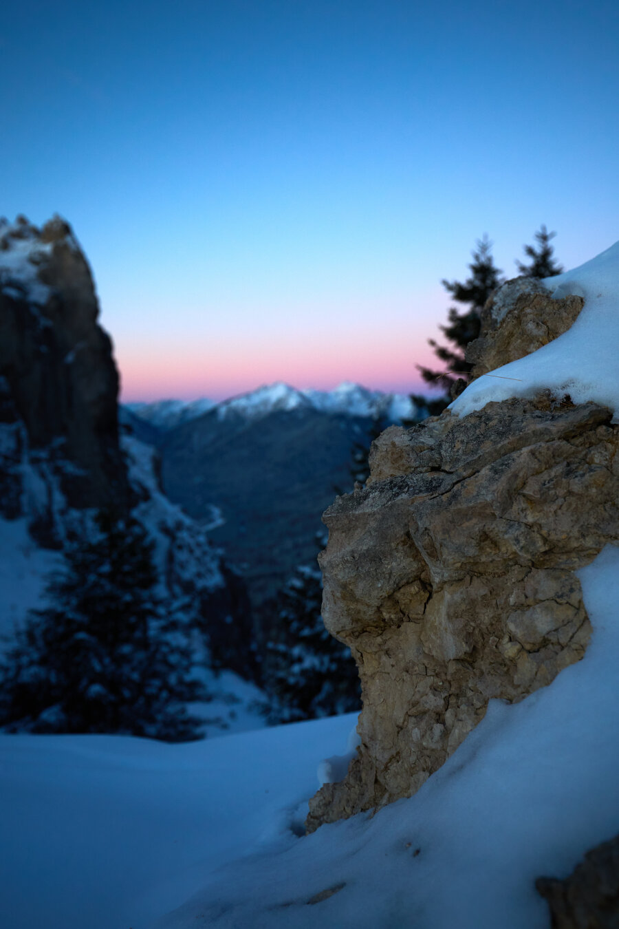A small rock with snow ontop and a beautiful dawn blurred in the background.