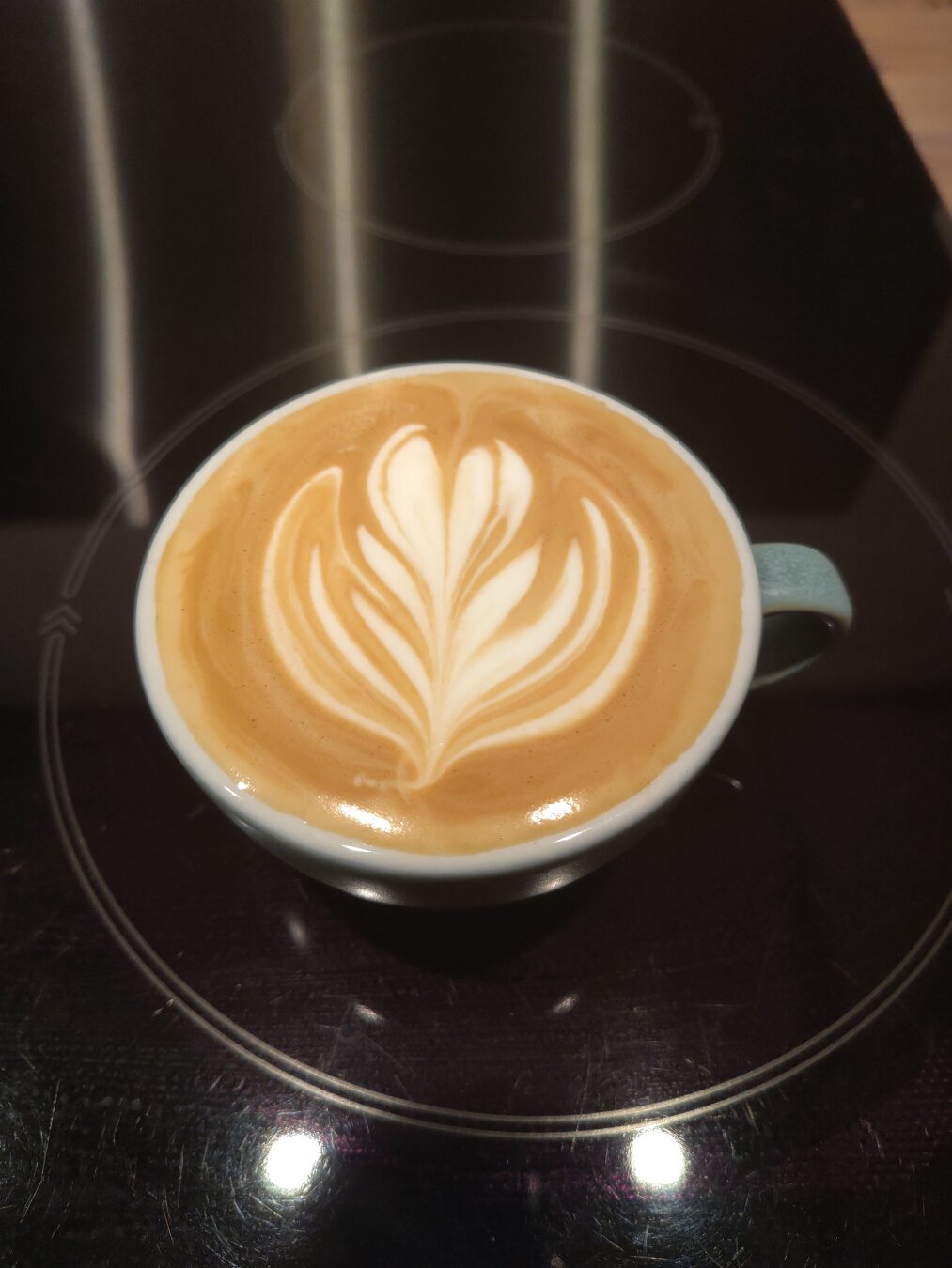 A cup of coffee with a latte art rosetta on top.